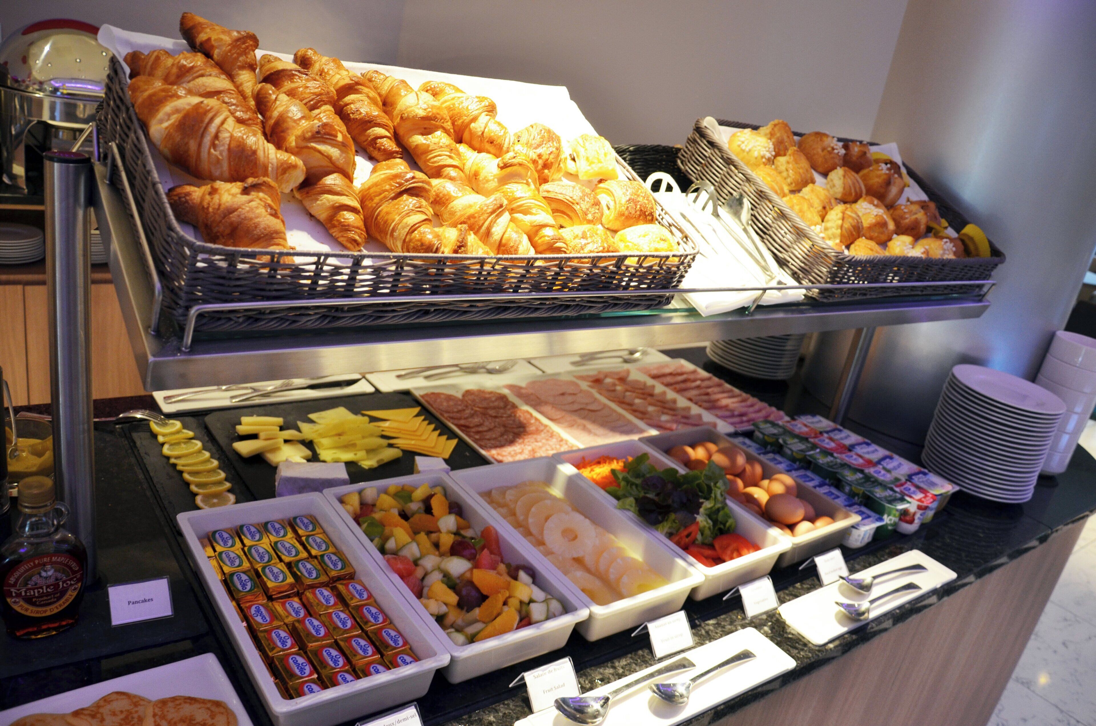 Un buffet proposant une variété de plats, notamment des pâtisseries, des fruits et des condiments.