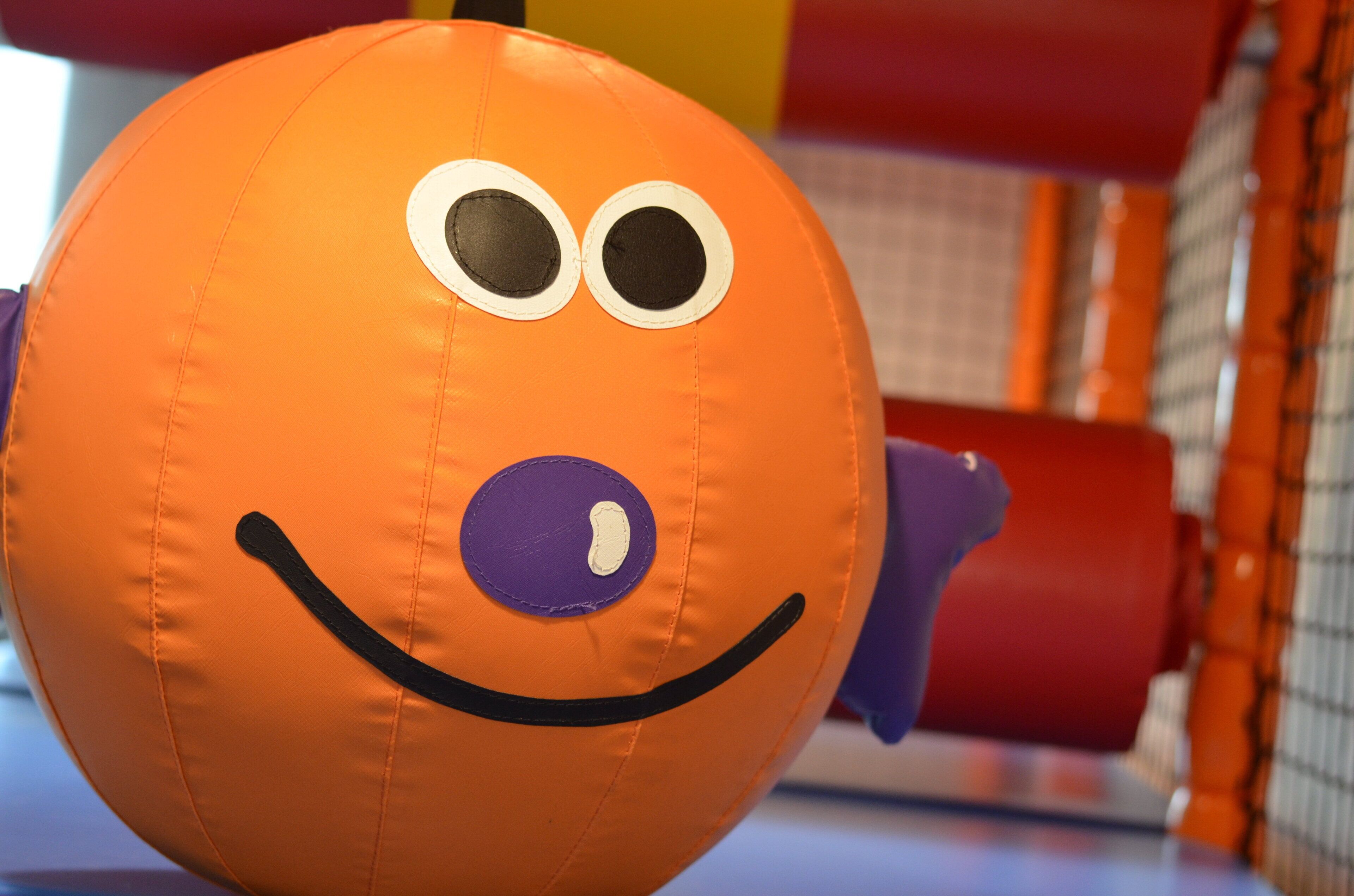 A colorful play structure with a ball featuring a face design.