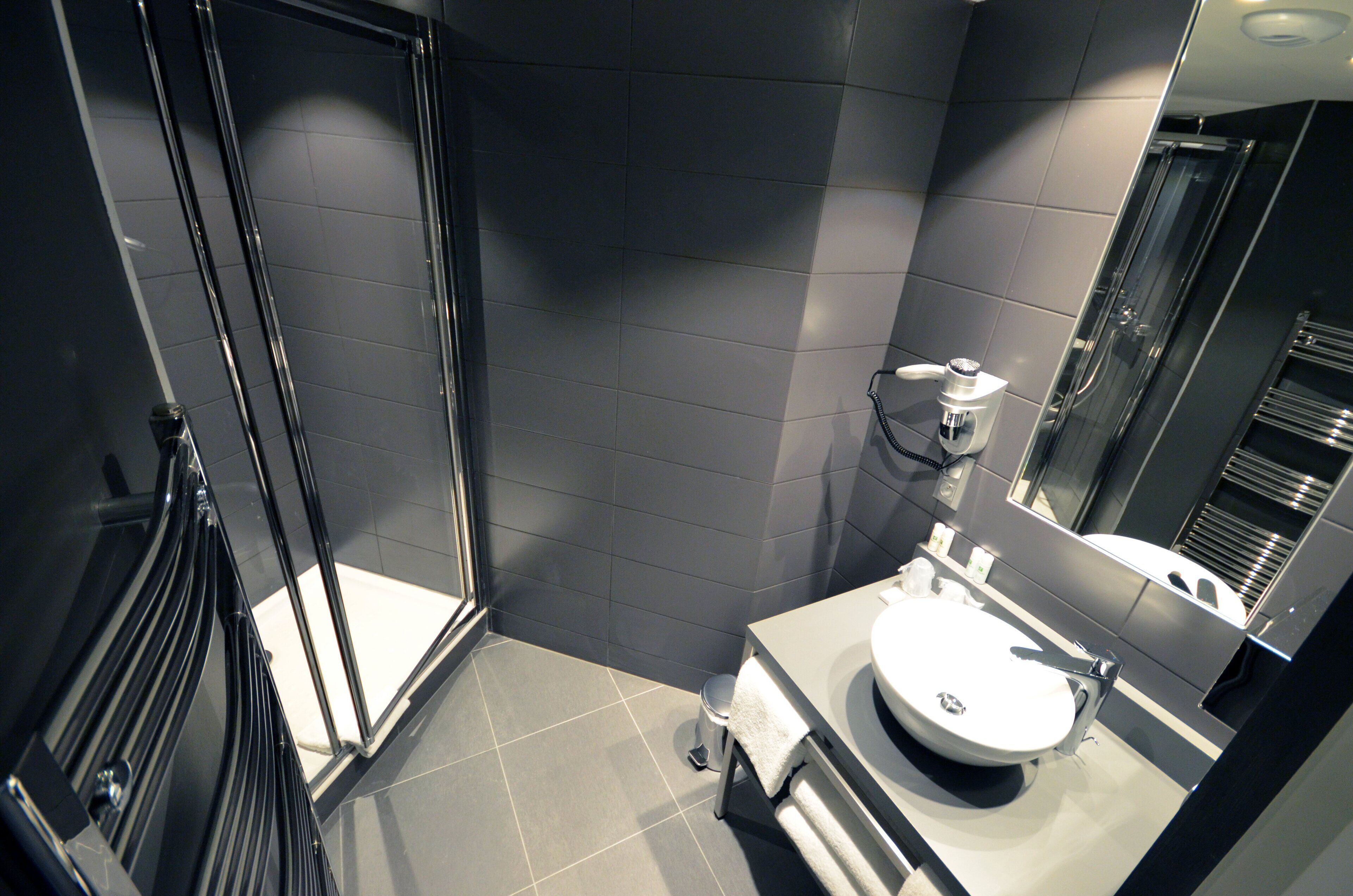 A modern bathroom with a glass shower enclosure, a white sink, and a large mirror.