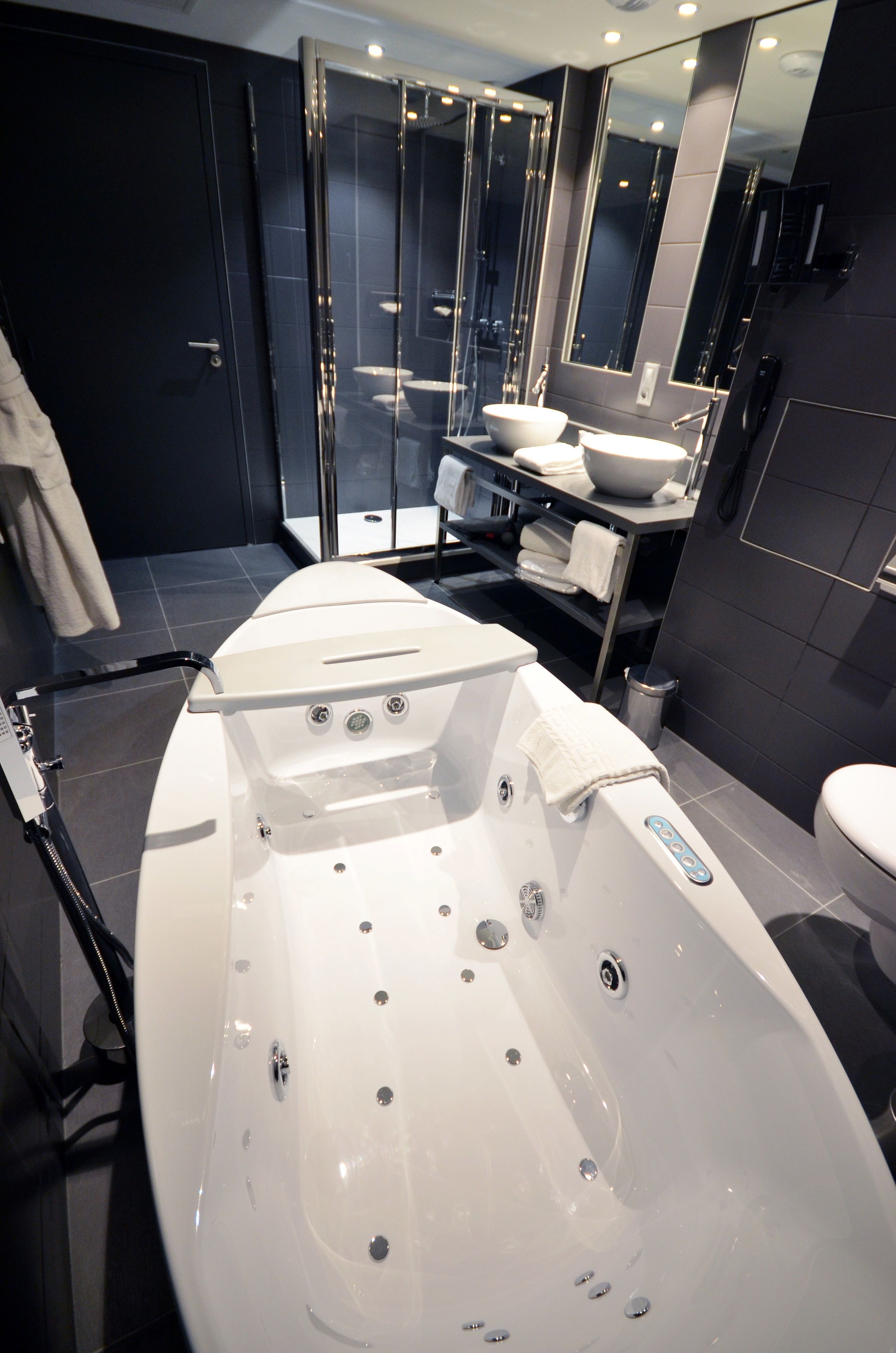 Une salle de bain moderne dotée d’une grande baignoire, d’une douche à parois de verre et d’un meuble-lavabo avec un évier et un miroir.
