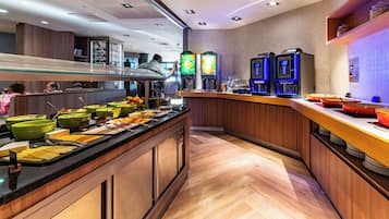 Zona de bufé con diferentes alimentos y dispensadores de bebidas.