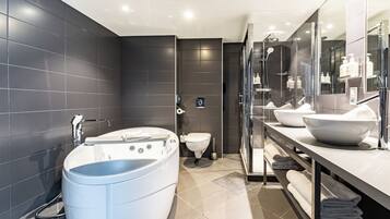Een moderne badkamer met een vrijstaand bad, een toilet en een wastafel met twee wasbakken.