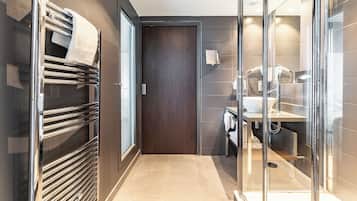 A modern bathroom with a glass shower enclosure, a sink, and a towel rack.