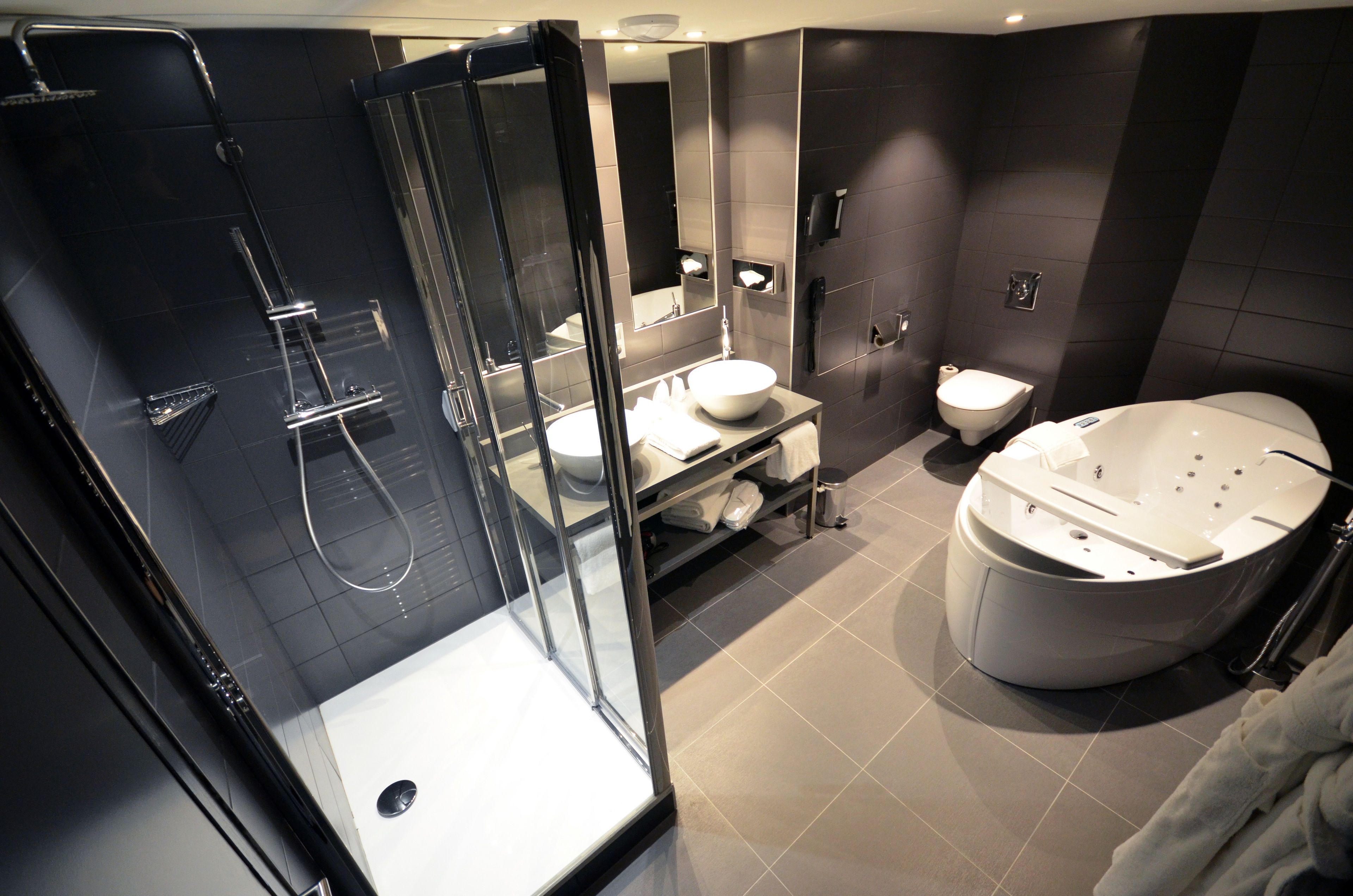 Une salle de bain moderne dotée d’une douche à parois de verre, d’une baignoire sur pieds, d’un meuble-lavabo et de toilettes.