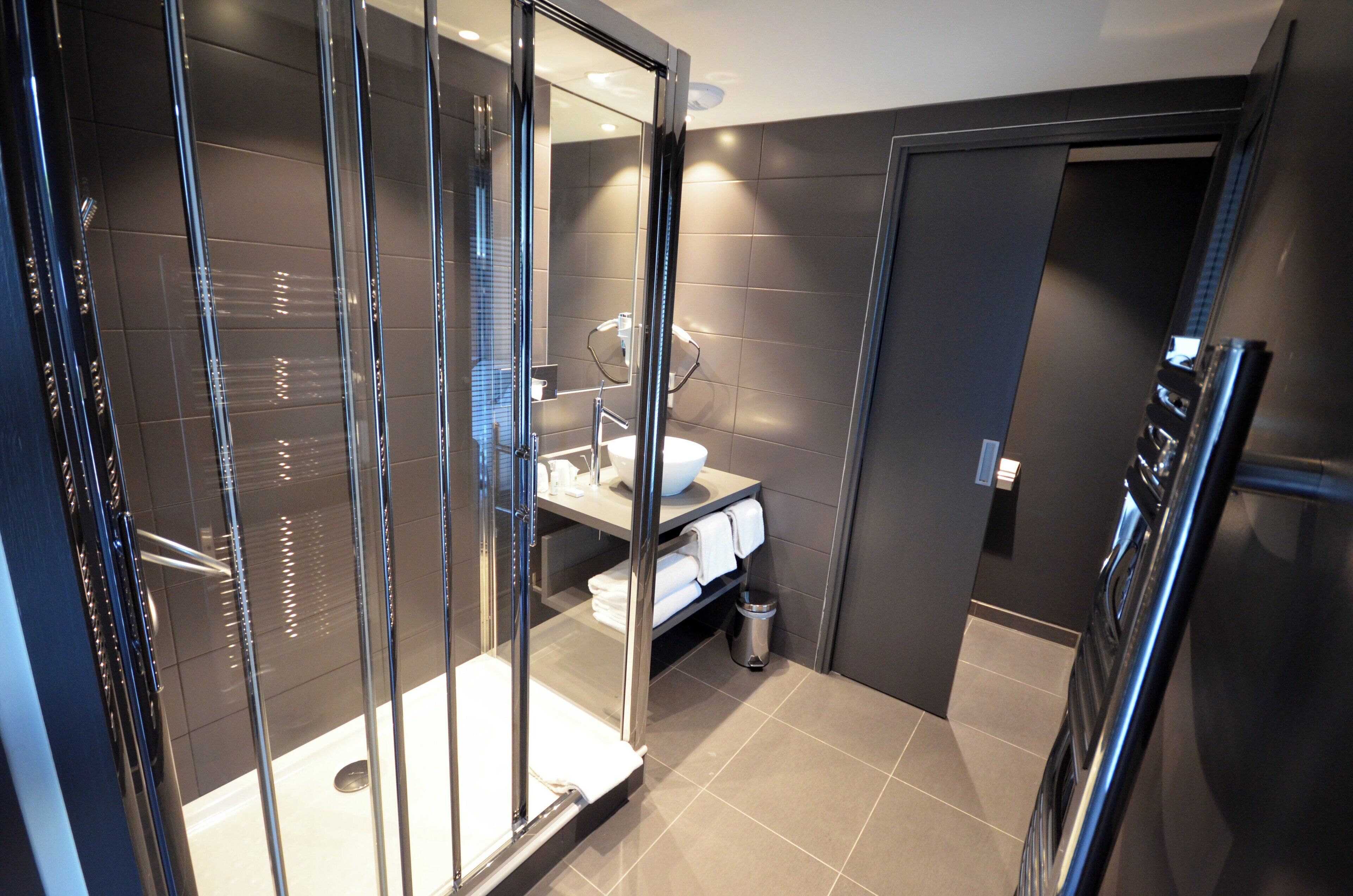 A modern bathroom with a glass-enclosed shower, a sink with a mirror, and a toilet.