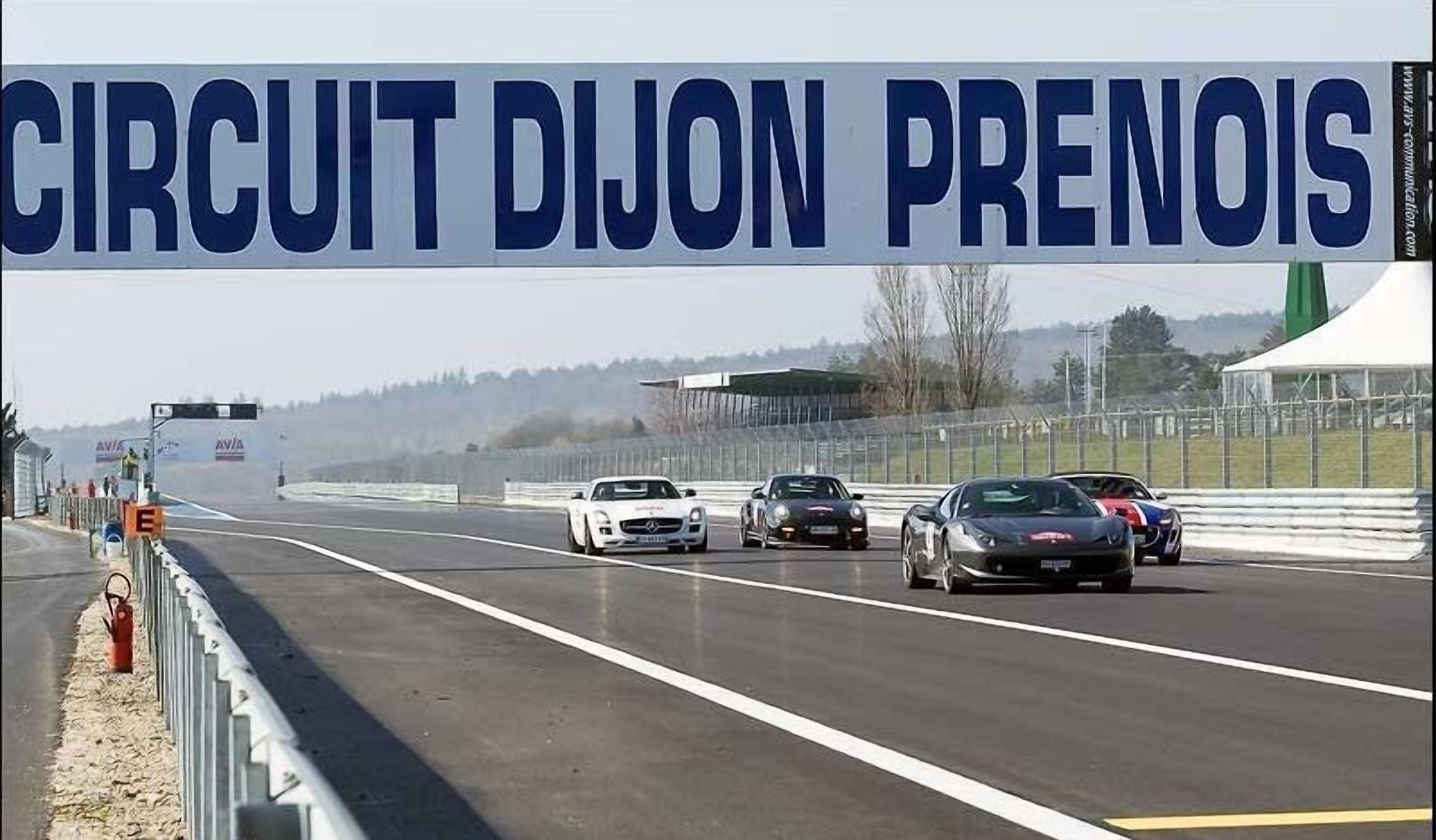A racing track with multiple cars and a large banner reading "CIRCUIT DIJON PRENOIS".