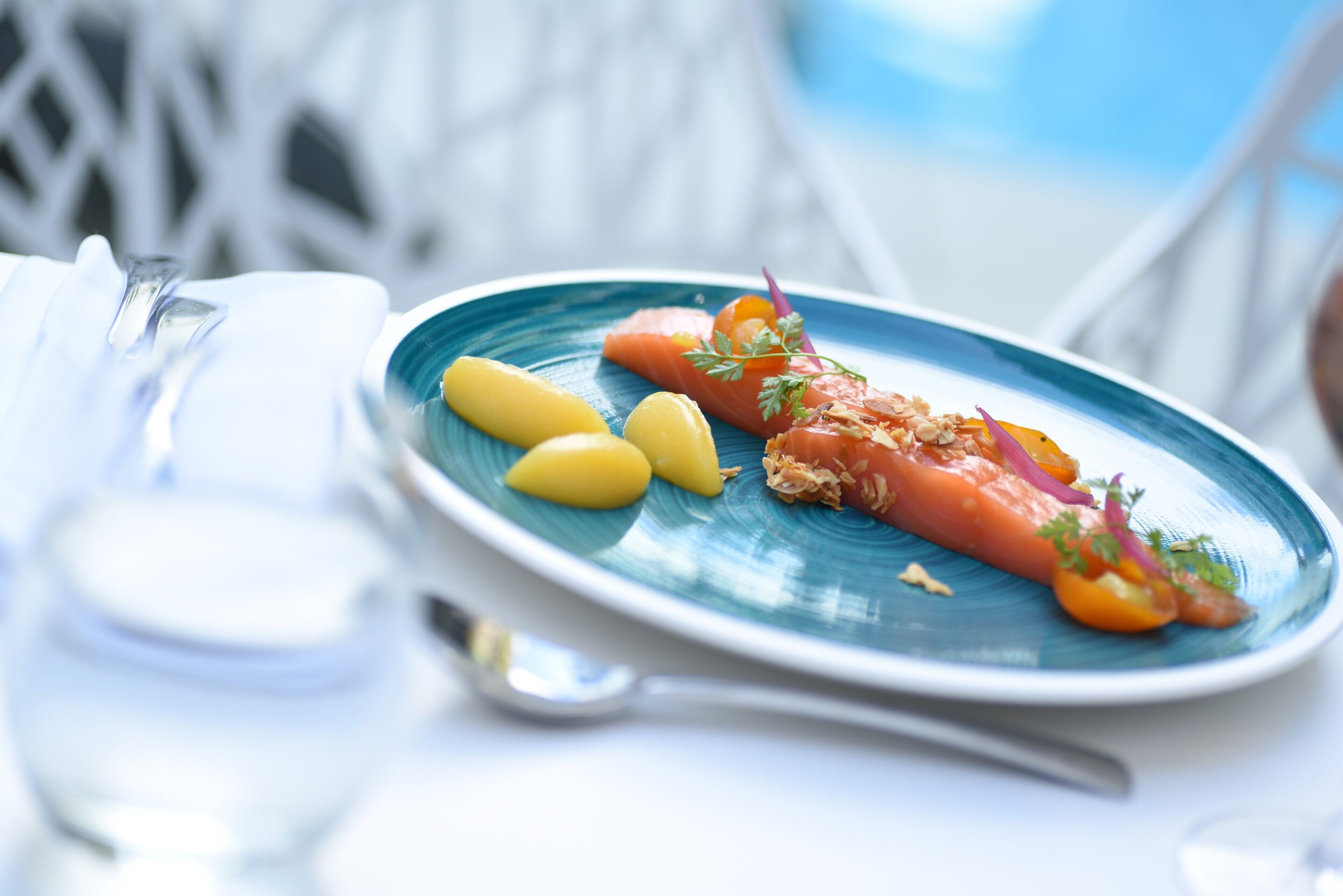A plate of food with salmon, lemon slices, and garnishes on a blue plate.