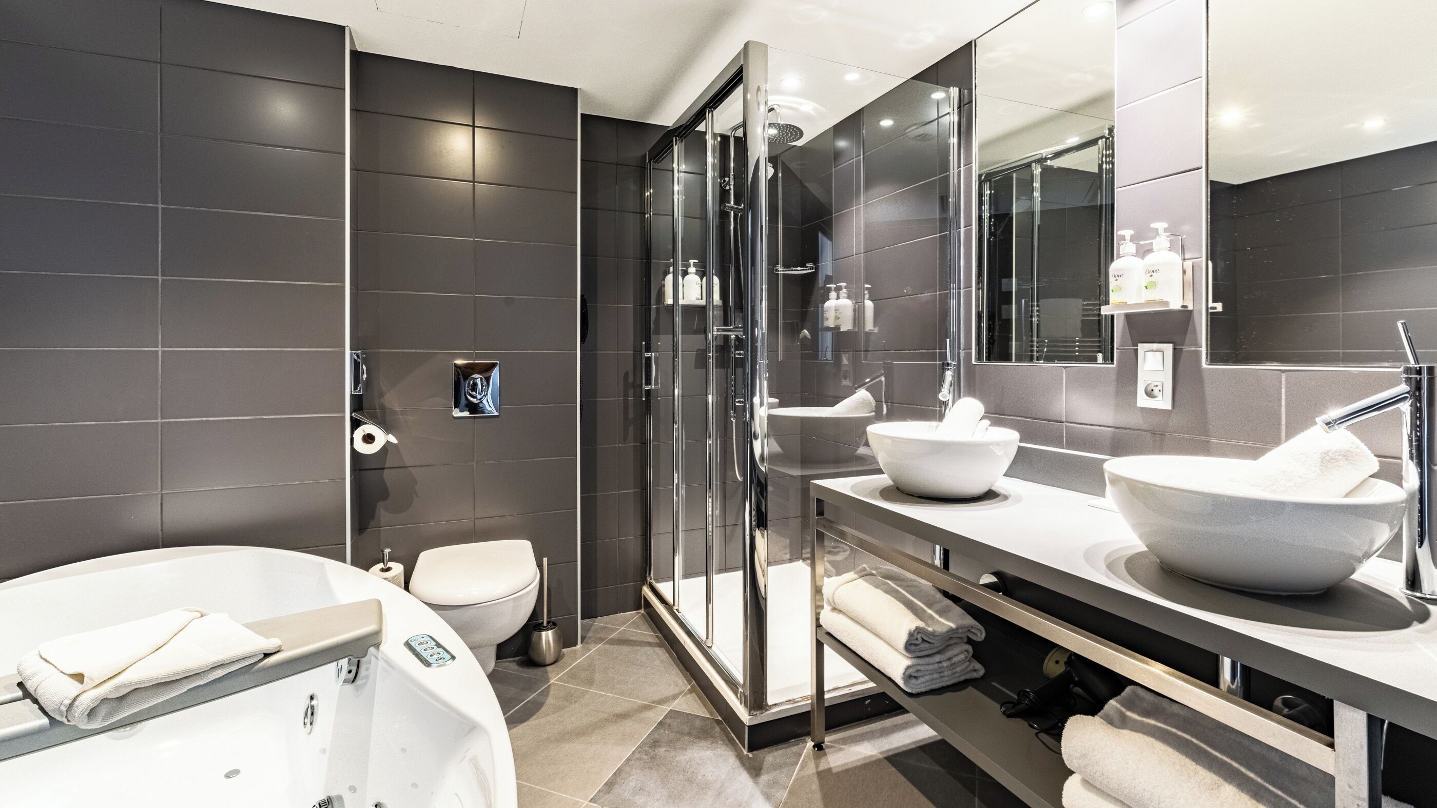 Une salle de bain moderne dotée d’une douche à parois de verre, d’une grande baignoire sur pieds et d’un meuble-lavabo avec deux vasques.