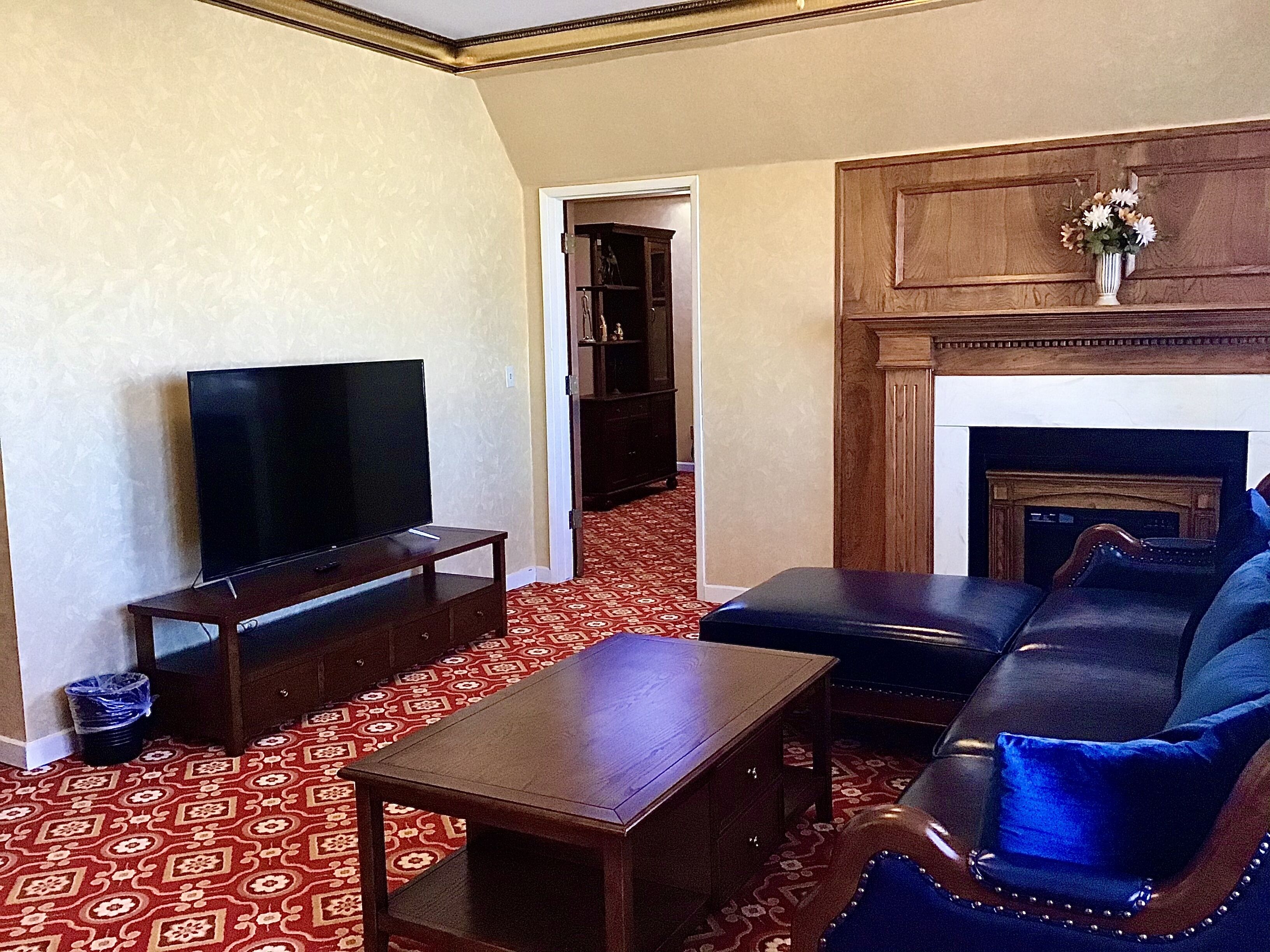 A living room with a television on a stand, a sofa, a coffee table, and a patterned carpet.