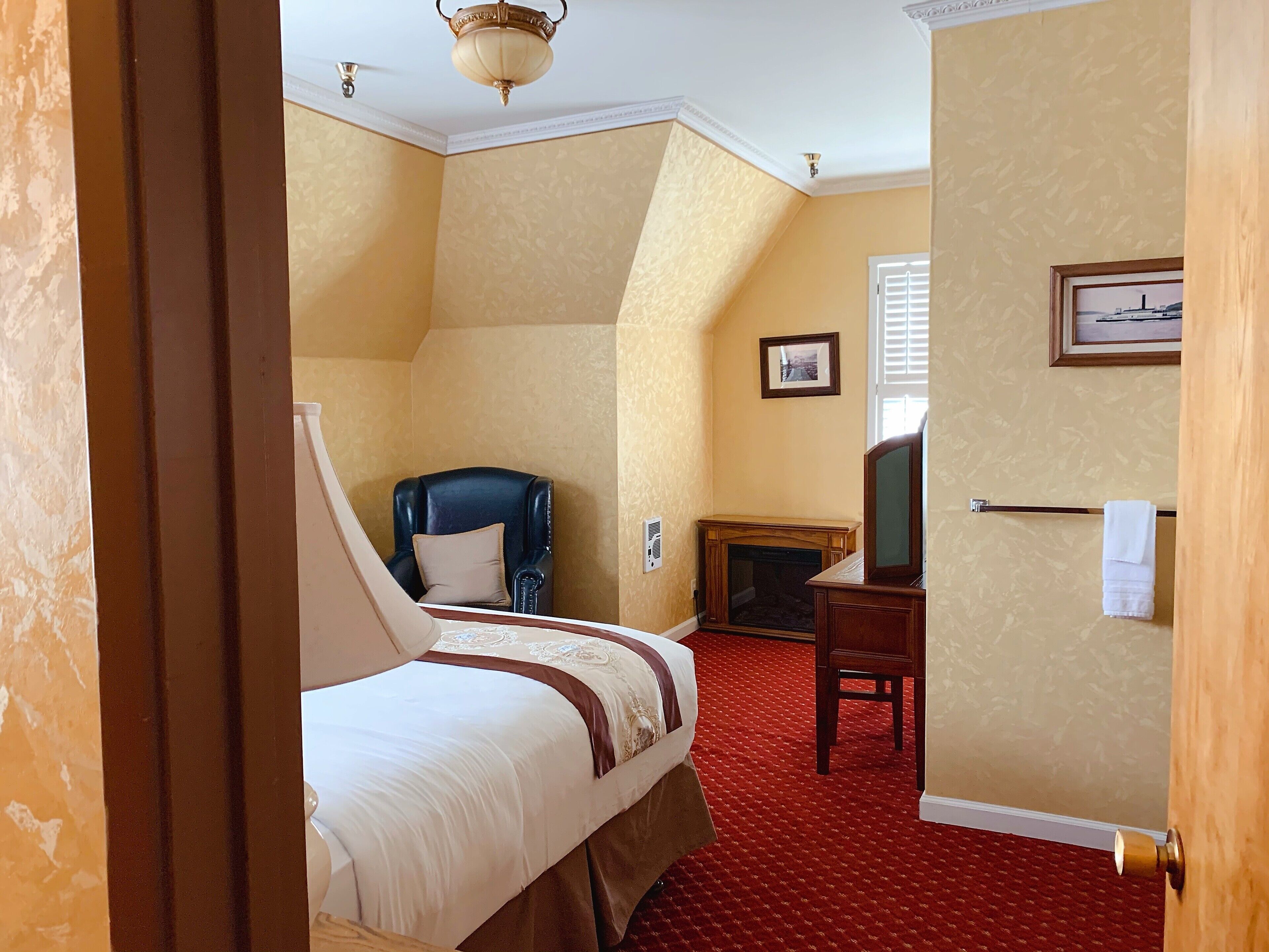 Une chambre d’hôtel avec un lit, une chaise, une cheminée et un téléviseur.