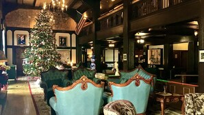 A lobby with a Christmas tree, two blue armchairs, and a patterned armchair.