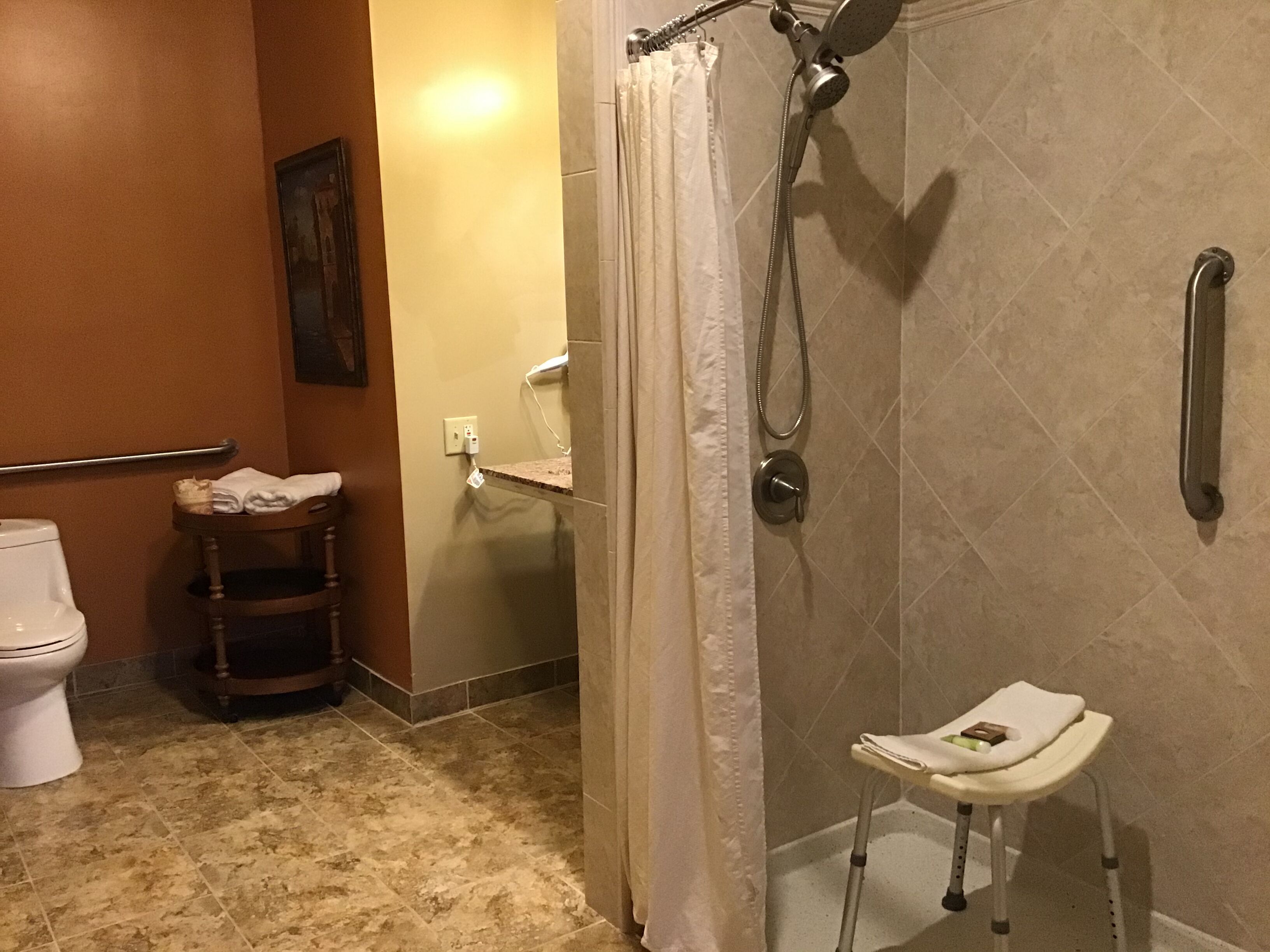 Un baño con ducha, inodoro y un taburete pequeño.
