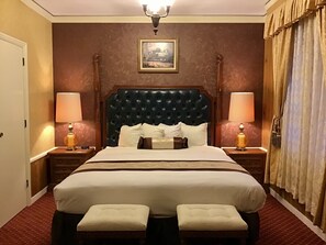 A hotel room with a large bed, two bedside lamps, a framed picture on the wall, and a window with curtains.