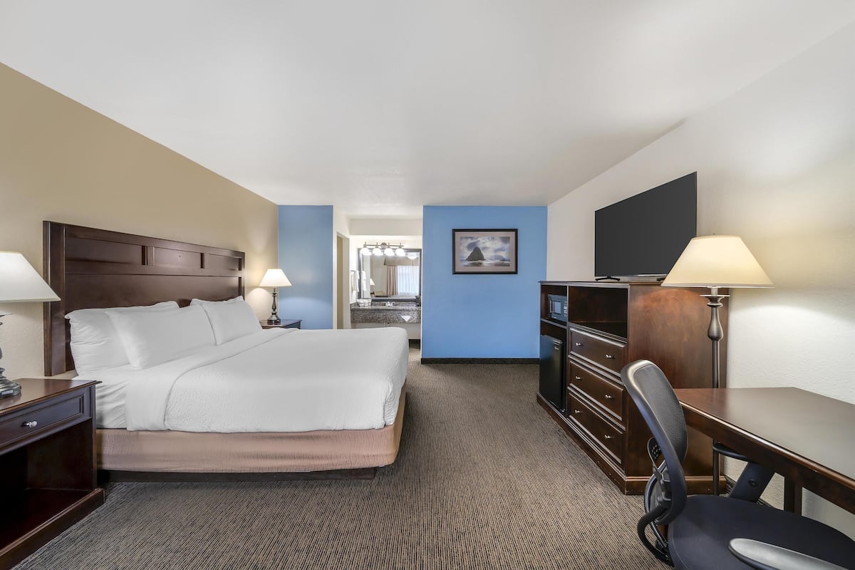 A hotel room with a bed, desk, chair, and a view of the bathroom.