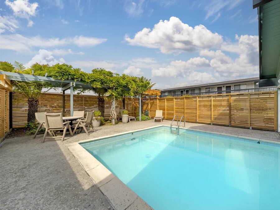 Une piscine rectangulaire dotée d’une terrasse en bois et de chaises longues.