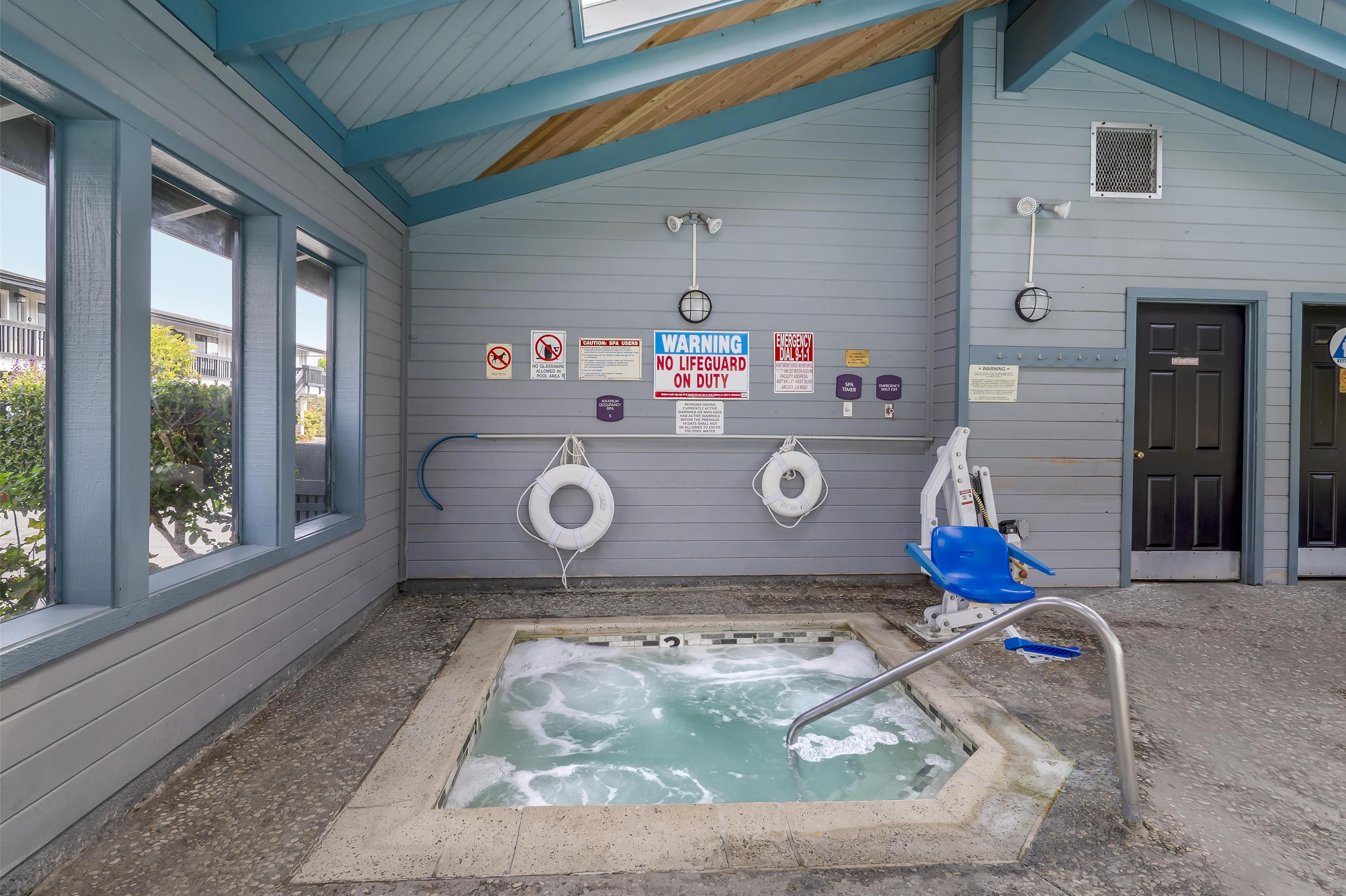 A spa area with a hot tub, safety signs, and lifebuoys.