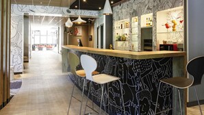 A bar area with a counter, bar stools, hanging pendant lights, and a patterned wall. - ibis Hyères Centre (Hyères)