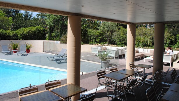 A poolside area with lounge chairs, tables, and a pool. - ibis Hyères Centre (Hyères)