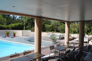 A poolside area with lounge chairs, tables, and a pool. - ibis Hyères Centre (Hyères)
