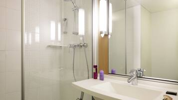 A modern bathroom with a glass shower enclosure, a white sink with a mirror, and a handheld showerhead.