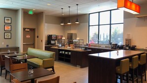 A modern cafe with a central island, seating area, and a large window providing a view.