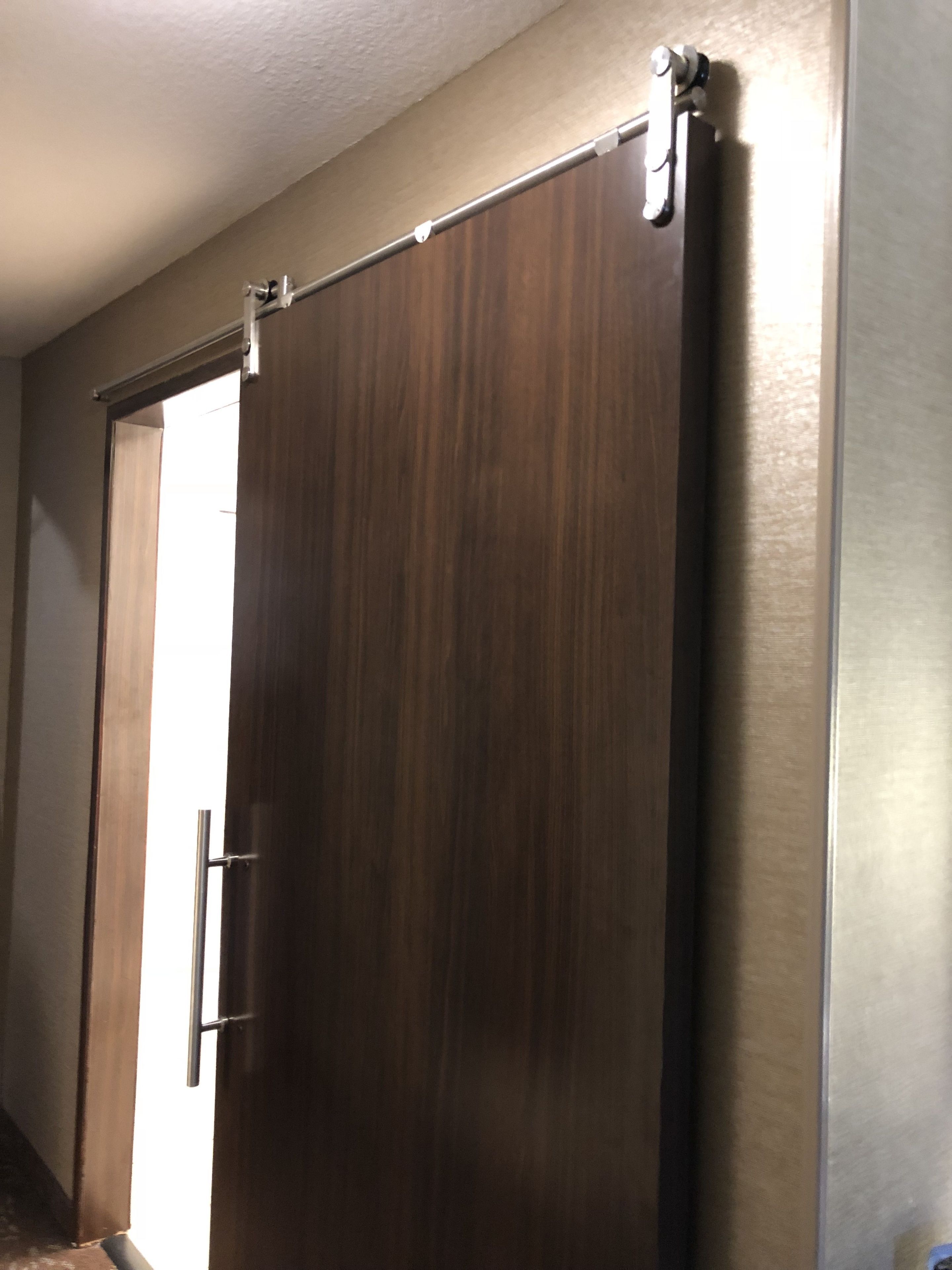 Puerta corrediza con manija metálica y sistema de rieles.