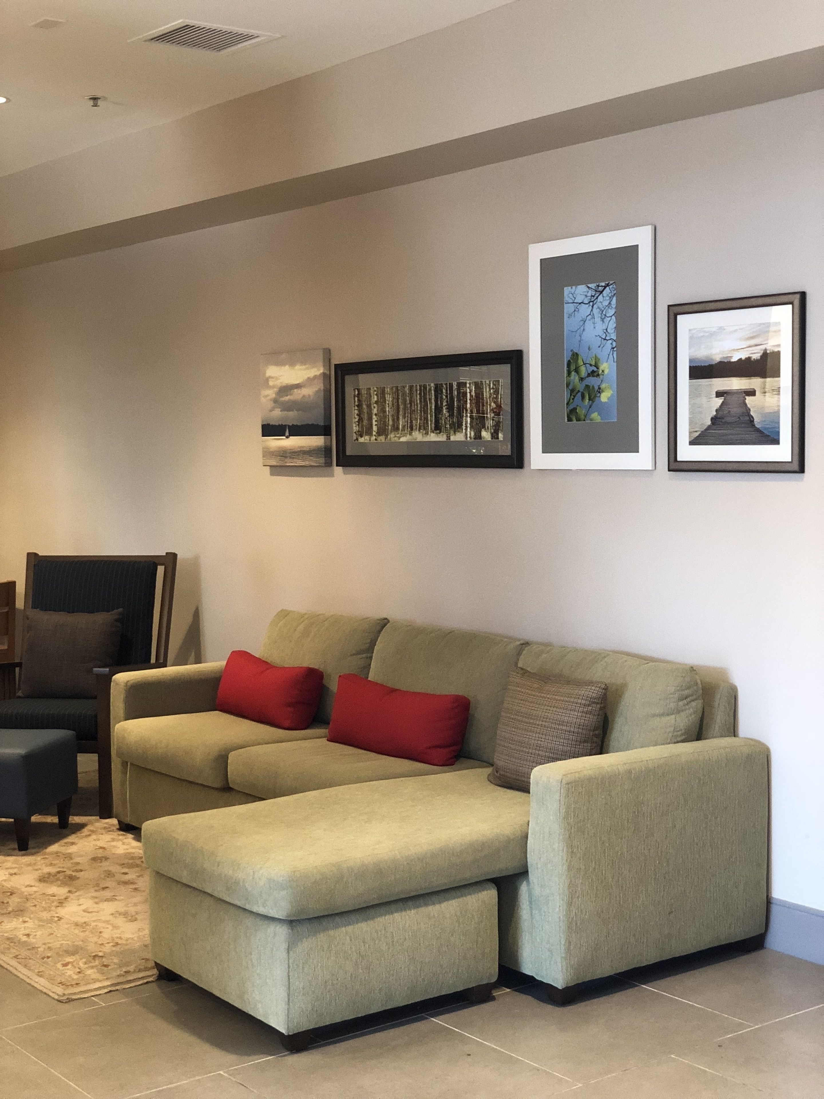 A living room with a sectional sofa, a chair, and a rug. There are three framed pictures on the wall.
