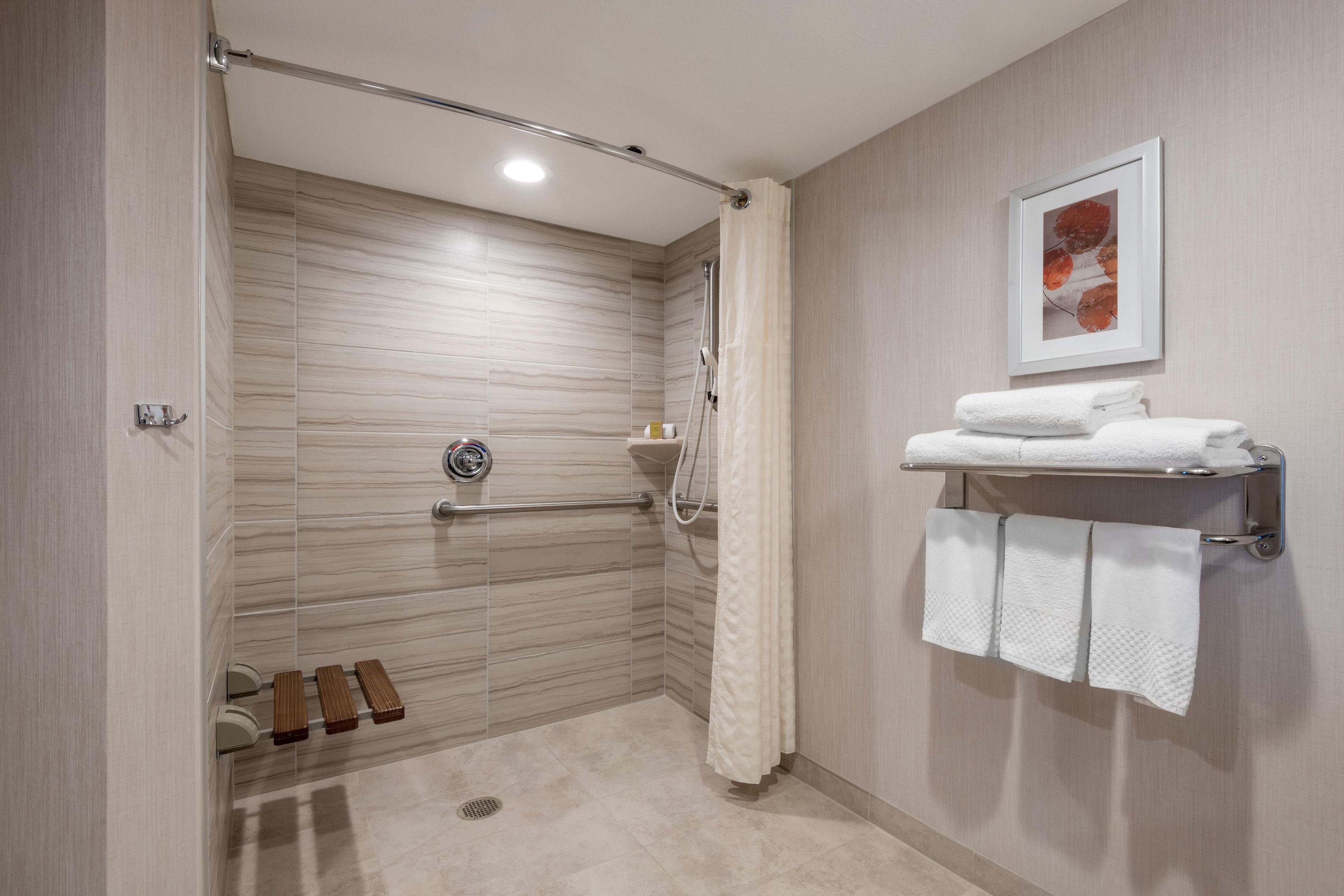 A modern bathroom with a shower, a hand dryer, and a towel rack.