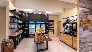 Un interior moderno con una mesa central, estantes llenos de refrigerios y una máquina de café.