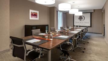 A conference room with a long table, multiple chairs, and a presentation screen.