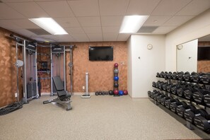 A gym with exercise equipment, a TV, and a mirror. - DoubleTree by Hilton Denver - Aurora (Aurora)