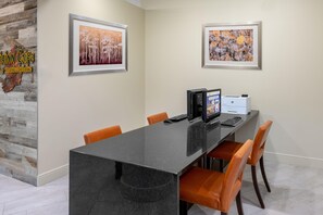 A conference room with a long table, chairs, a computer, and two framed pictures on the wall.