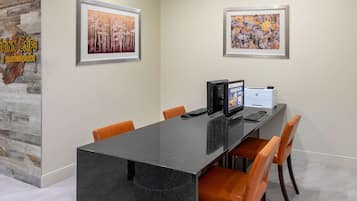 Un salón de conferencias con una mesa de mármol, sillas anaranjadas, obras de arte enmarcadas en las paredes y una impresora.