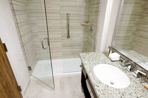 A modern bathroom with a glass-enclosed shower, a granite countertop, and a large mirror. - DoubleTree by Hilton Denver - Aurora (Aurora)