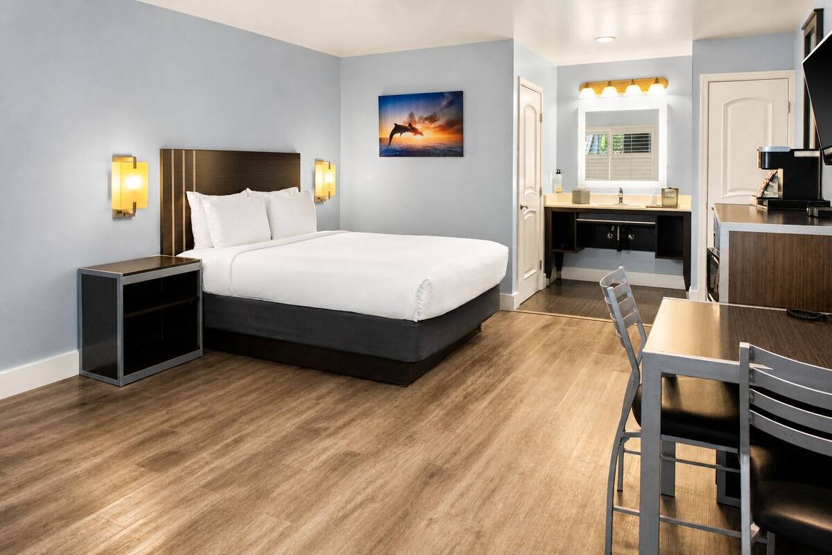 A hotel room with a bed, bedside table, desk, and chair.