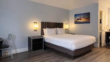 A hotel room with a large bed, bedside tables, a chair, and a painting on the wall.