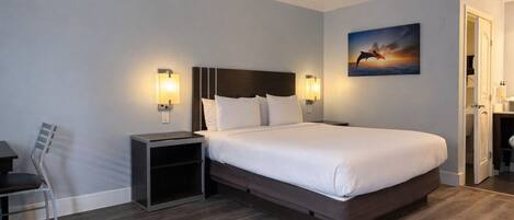 A hotel room with a large bed, bedside tables, a chair, and a painting on the wall.