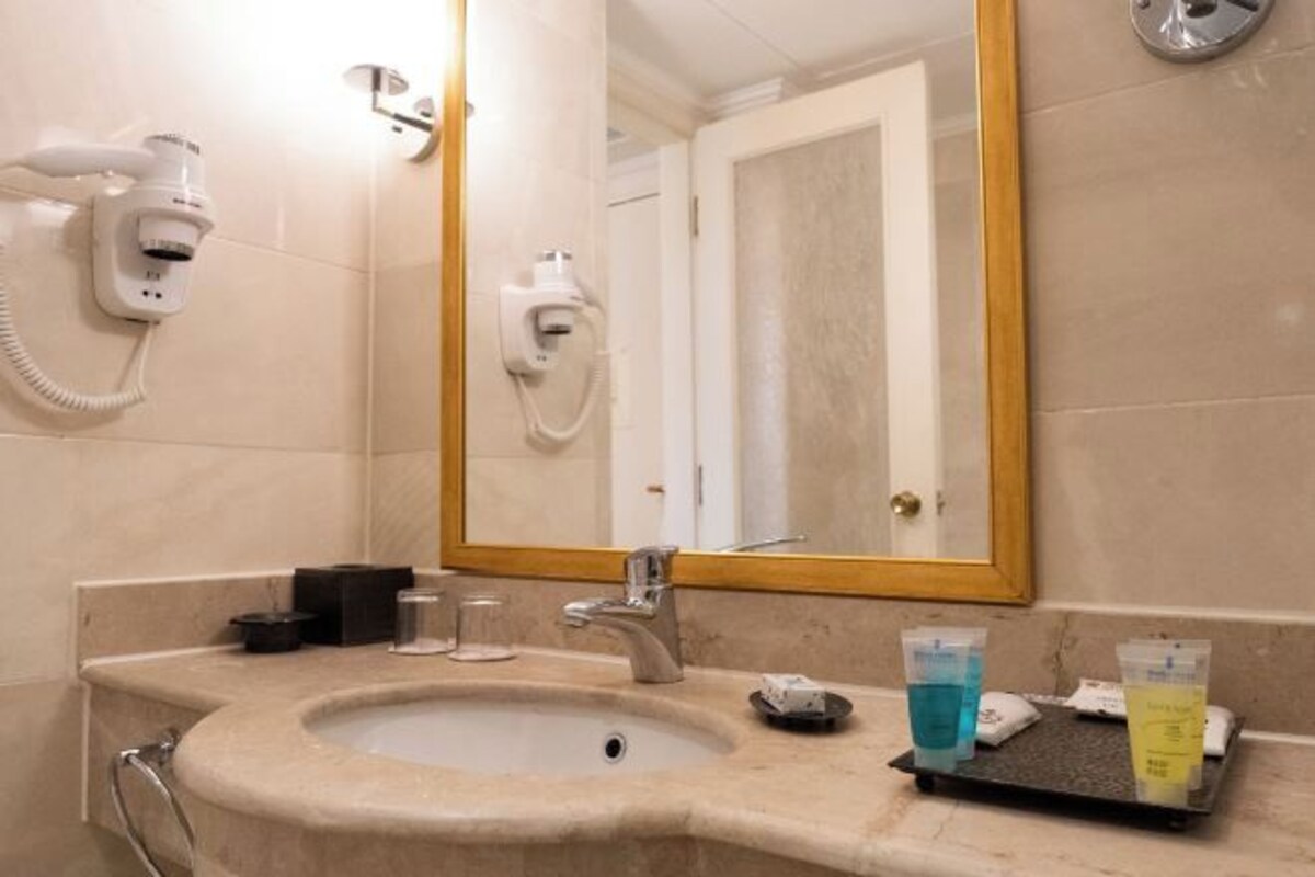 A bathroom with a sink, mirror, and toiletries.