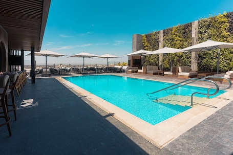 Una piscina al aire libre, sombrillas, sillones reclinables de piscina. Baron Hotel Cairo