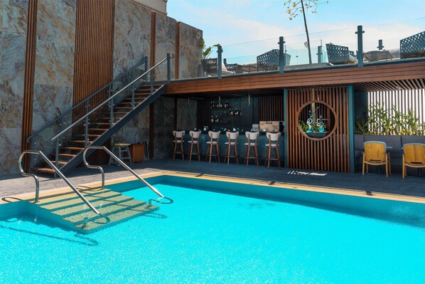 A swimming pool with a bar area, wooden seating, and a staircase. - Baron Hotel Cairo (Cairo)