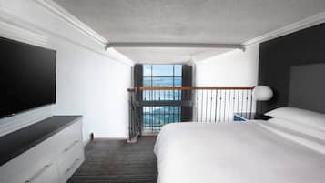 Une chambre d’hôtel dotée d’un grand lit, d’une télévision à écran plat, d’une commode et d’un balcon offrant une vue sur la mer.