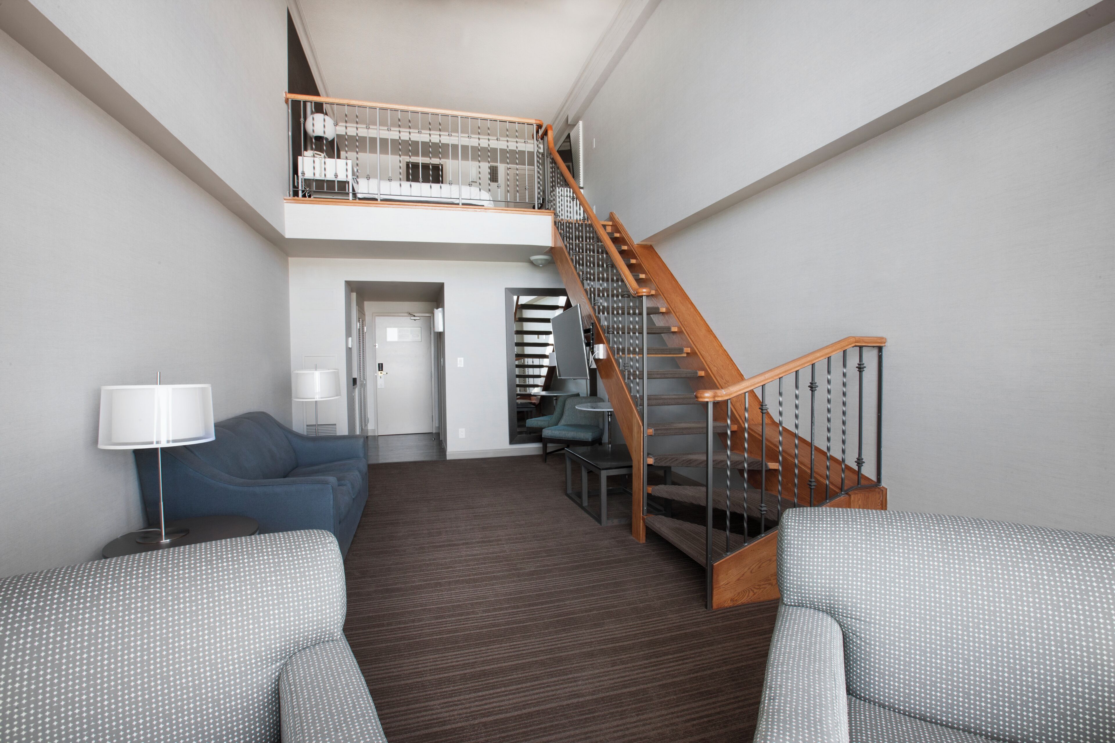 A modern interior with a staircase, a sofa, a lamp, and a bookshelf.