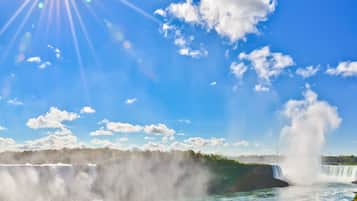 A waterfall with mist, a clear sky, and sunlight.