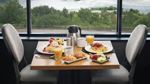 A breakfast table with plates of food, a coffee pot, and a view of a waterfall. - Niagara Falls Marriott on the Falls (Niagara Falls)