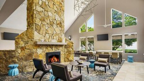 Un espacio interior amplio con chimenea de piedra, asientos cómodos y grandes ventanales con vistas al exterior.