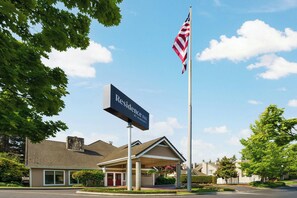 A hotel with a prominent American flag, a sign reading "Residence Inn by Marriott," and a covered entrance. - Residence Inn by Marriott Seattle North-Lynnwood Everett (Lynnwood)