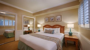 A hotel room with a large bed, two bedside tables with lamps, a mirror, and framed pictures on the wall. - Carmel Bay View Inn (Carmel)