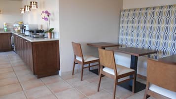 A modern kitchen with a central island, wooden chairs, and a patterned wall.
