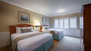 A bedroom with two beds, a nightstand, a lamp, and a window with blinds.