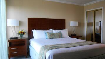 A hotel room with a large bed, two bedside tables with lamps, a mirror, and a wooden headboard.
